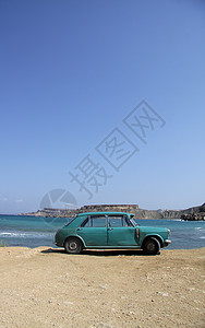 一辆老旧的生锈汽车丢弃在沙滩上图片
