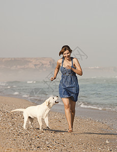 女孩带着她的狗喜悦猎犬闲暇幸福友谊微笑海岸海滩乐趣宠物图片