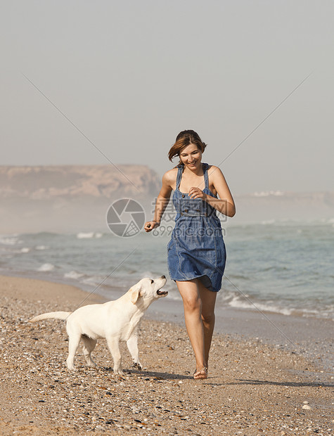 女孩带着她的狗喜悦猎犬闲暇幸福友谊微笑海岸海滩乐趣宠物图片