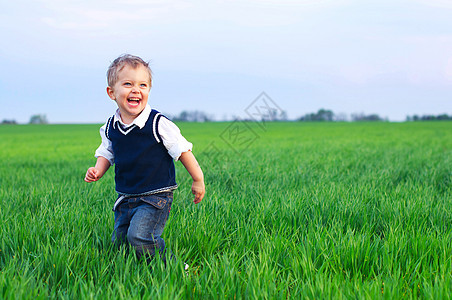 一个美丽的小男孩跑在草地上幸福花园童年孩子蓝色闲暇晴天花朵情绪男生图片