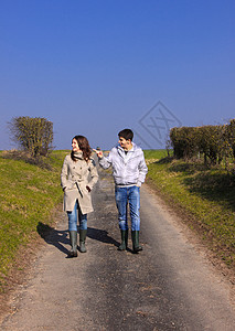 在春季运动中走着一对年轻人的青年朋友笑声夫妻天空友谊青少年民谣蓝色跑步微笑图片