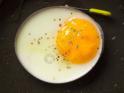 煎蛋戒指白色蛋黄早餐金属平底锅水平食物黑色背景图片