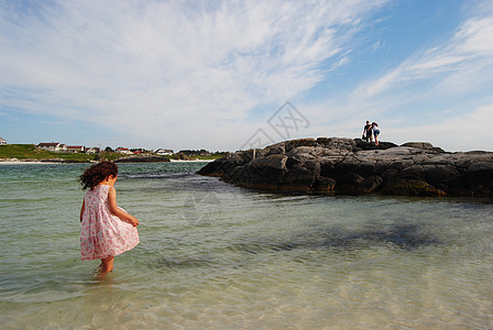 女孩在海中孩子蓝色海洋头发女性海滩天空裙子岩石海岸图片