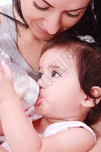 母亲和婴儿在白种背景中喝瓶装牛奶图片