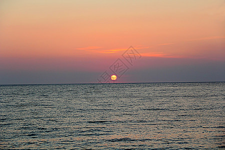 美丽的夜晚海景和日落的夕阳玫瑰圆形红色海洋地平线天空波浪太阳灰色图片