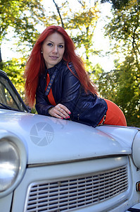 在旧车旁边的红发女孩情感红色女性化妆品发型汽车头发女士车辆冒充图片