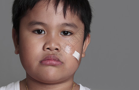 一个年轻男孩的肖像划痕情感急救病人绷带愈合帮助男性创伤皮肤图片