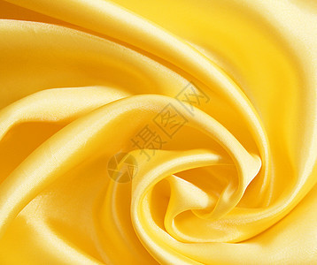 平滑优雅的金色丝绸可用作背景投标织物海浪涟漪材料纺织品黄色折痕曲线布料图片
