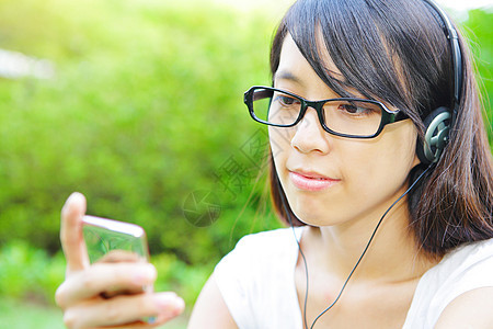 年轻女孩听音乐耳机享受闲暇娱乐公园音乐女性绿色青年玩家图片