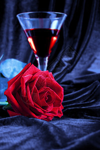 红玫瑰和酒在玻璃杯中图片