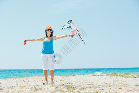 海滩上的女人玩着多彩的风筝喜悦情感闲暇享受空气晴天天空活动娱乐女孩图片