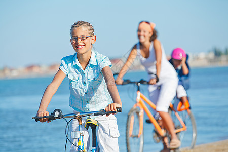 可爱的女孩和她的母亲和兄弟一起骑自行车金发女性海洋喜悦闲暇孩子幸福女士娱乐蓝色图片