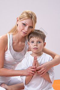 一个美丽的年轻母亲 和儿子一起做瑜伽幸福姿势白色身体孩子运动男生女士童年家庭图片