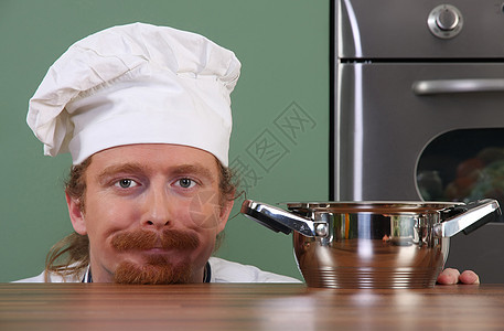 带着锅子的有趣的年轻厨师工作厨房帽子工人乐趣餐厅烤箱职业白色盘子图片