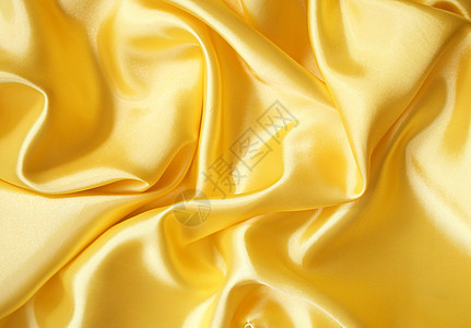 平滑优雅的金色丝绸可用作背景涟漪投标布料黄色曲线纺织品织物折痕材料图片