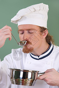 年轻厨师用桌边餐桌上的面粉来品尝食物工作餐厅帽子汤匙工人衣服午餐男人美食盘子图片