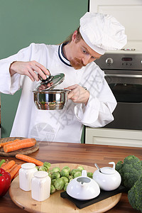 有趣的年轻厨师 奇怪地看着锅帽子职业餐具盘子服务厨房午餐男性工作男人图片