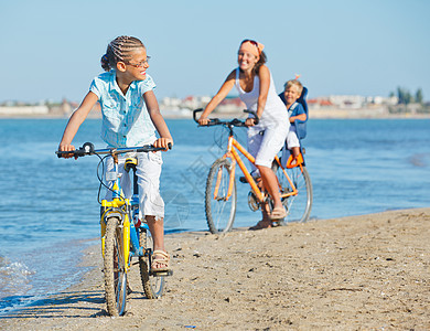 可爱的女孩和她的母亲和兄弟一起骑自行车波浪男生孩子快乐活动儿子公园运动娱乐蓝色图片