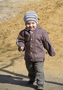 男孩穿着温暖衣服在操场上行走图片