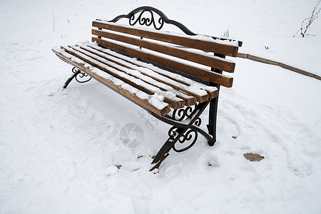 城市公园的独雪覆盖板凳图片