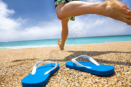 男人在海滩上奔跑和拖鞋图片