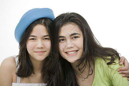 两个十几岁的女孩一起微笑 拥抱兄弟姐妹女士友谊乐趣少数民族混血儿蓝色姐妹混血绿色图片