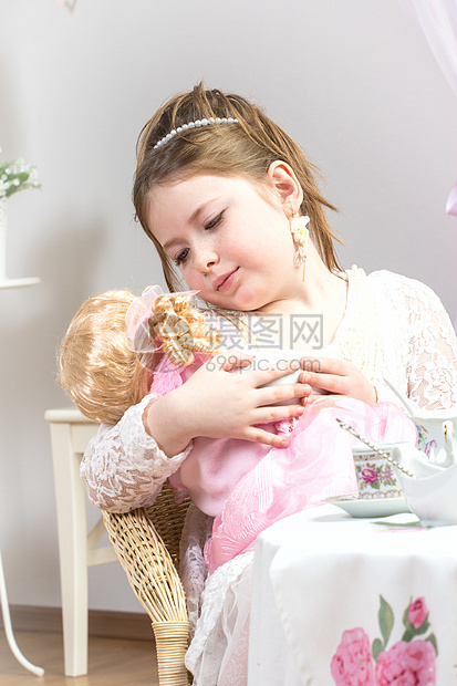 一个美丽的小女孩 和她的娃娃宝宝在茶会上玩图片