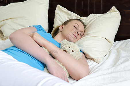 年轻女孩和泰迪熊睡着童年玩具说谎就寝软垫卧室女性睡眠蓝色时间图片