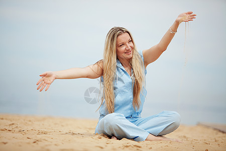 女人睡在沙滩上休息女士闲暇女性头发旅行金发蓝色假期快乐图片