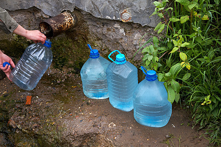女性手握着装有水的塑料瓶地下水来源气泡苔藓环境临界点石头塑料流动卵石图片