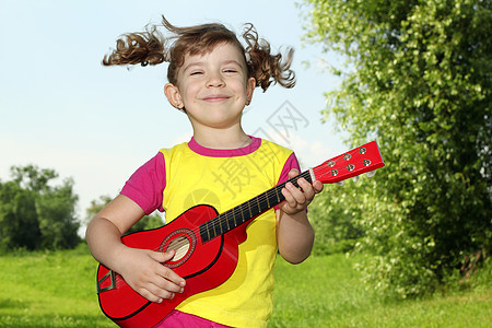 快乐的小女孩在户外弹吉他图片