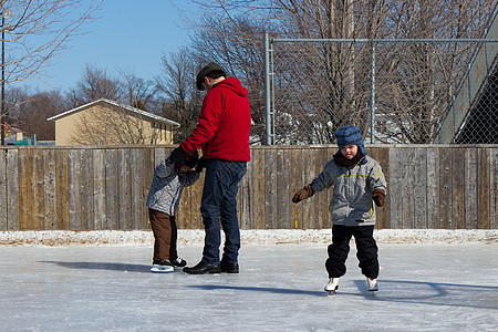 家庭在滑冰场爸爸挑战溜冰场姐姐团体帮助三个人活动兄弟曲棍球图片