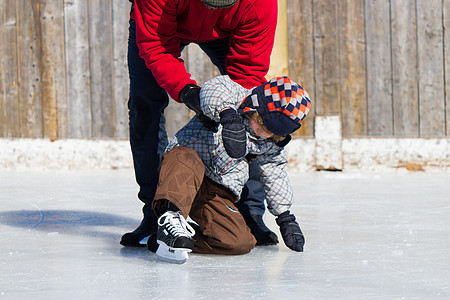 父亲教儿子如何滑冰活动帮助平衡家庭时间两个人爸爸孩子学习冬装图片