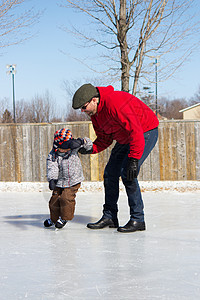 父亲教儿子如何滑冰冬装时间帮助活动家庭溜冰场爸爸男性男生两个人图片