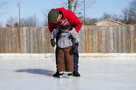 父亲教儿子如何滑冰男性帮助父母两个人时间活动爸爸冬装学习平衡图片