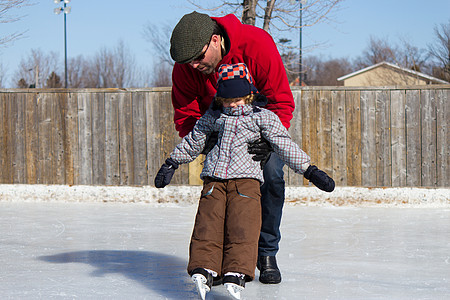 父亲教儿子如何滑冰家庭孩子溜冰场平衡时间父母活动帮助晴天男性图片
