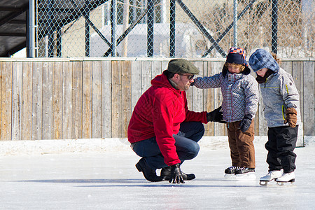 家庭在滑冰场玩得开心晴天孩子们曲棍球三个人溜冰场女性活动冬装团体孩子图片