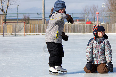 滑冰场的孩子溜冰场活动兄弟滑冰男生女孩家庭晴天两个人时间图片