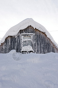 寒冷的冬天下午 屋顶和窗户是一栋木制小房子的窗子 里面有雪图片