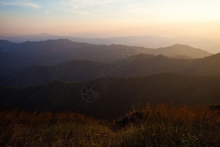 山边日落太阳射线山脉顶峰岩石地平线天空图片