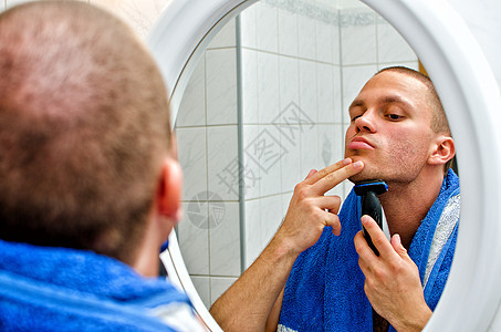 男人在镜子前的浴室里刮毛巾专注胡须护理卫生剃刀剃须反射皮肤剃须刀修饰图片