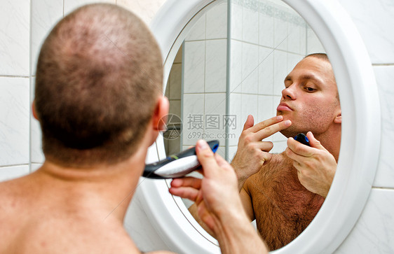 男性在浴室刮胡子 在镜子前剃须胡须反射男人卫生修饰肩膀脖子护理剃须刀图片