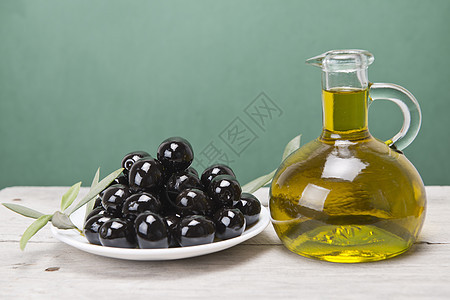 黑色橄榄和油的盘子烹饪沙拉木头商业叶子调味品美食收成树叶小吃图片