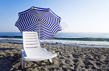 蓝色海岸上独有伞子的捕猎休息室图片