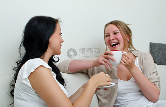 两个女人朋友在家喝咖啡聊天 在家里聊着咖啡休息室黑发杯子工人友谊讨论女士沙发房间讲话图片