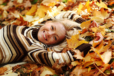 秋叶中的妇女脚尖女孩橙子眼睛幸福毛衣公园金发女郎女性季节团体图片