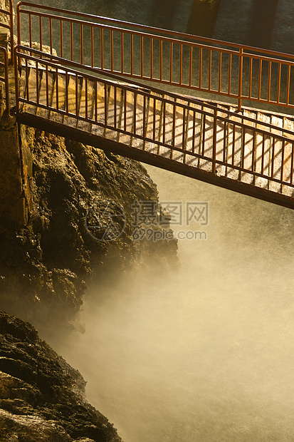 夜间在野生河流和岩石上架设窄木制钢桥图片