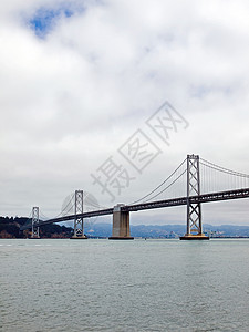 旧金山湾大桥在云天建筑工程城市旅行电缆历史性运输水路地标天空图片