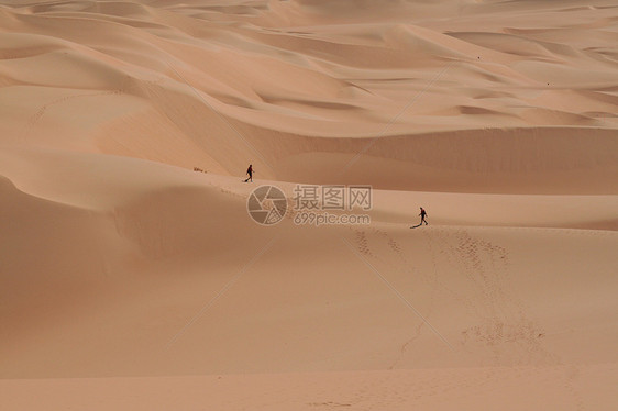 两人在撒哈拉沙漠中行走旅行风景橙子气候沙丘晴天男人侵蚀干旱太阳图片