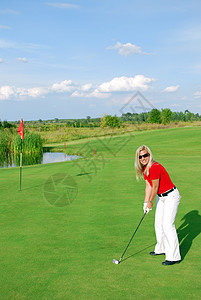 在高尔夫球场打高尔夫的金发女孩图片